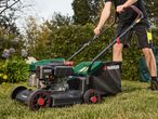 A person uses a Masport petrol lawn mower to cut grass.