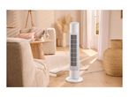White tower fan in a bright living room with a sofa, coffee table, and woven decor.