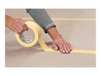 Hands applying masking tape to a surface, creating a straight line.