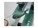A person wearing a glove uses a hacksaw to cut a metal profile on a workbench.