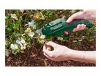 Hands pruning white flowers on a bush with a green electric garden shear.