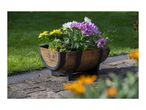 Barrel-shaped planter with colorful chrysanthemums and ornamental kale on a paved patio.