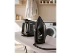 Ferro a vapor SilverCrest preto e unidade base numa tábua de engomar.