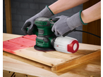 Person using a Parkside® sander on a red wooden surface, with a dust collection box attached.
