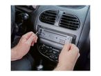 A person using removal keys to extract a car radio from the dashboard.