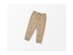 A pair of beige sweatpants with a pattern of dog faces and the word 'ADVENTURE'.