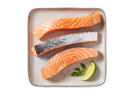 Três pedaços de salmão cru com pele, uma fatia de lima e salsa num prato cinzento.