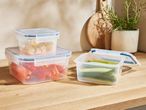 Stackable, clear plastic food storage containers on a kitchen counter.