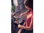 Woman cooking meat rolls with sage in a frying pan on an induction hob.