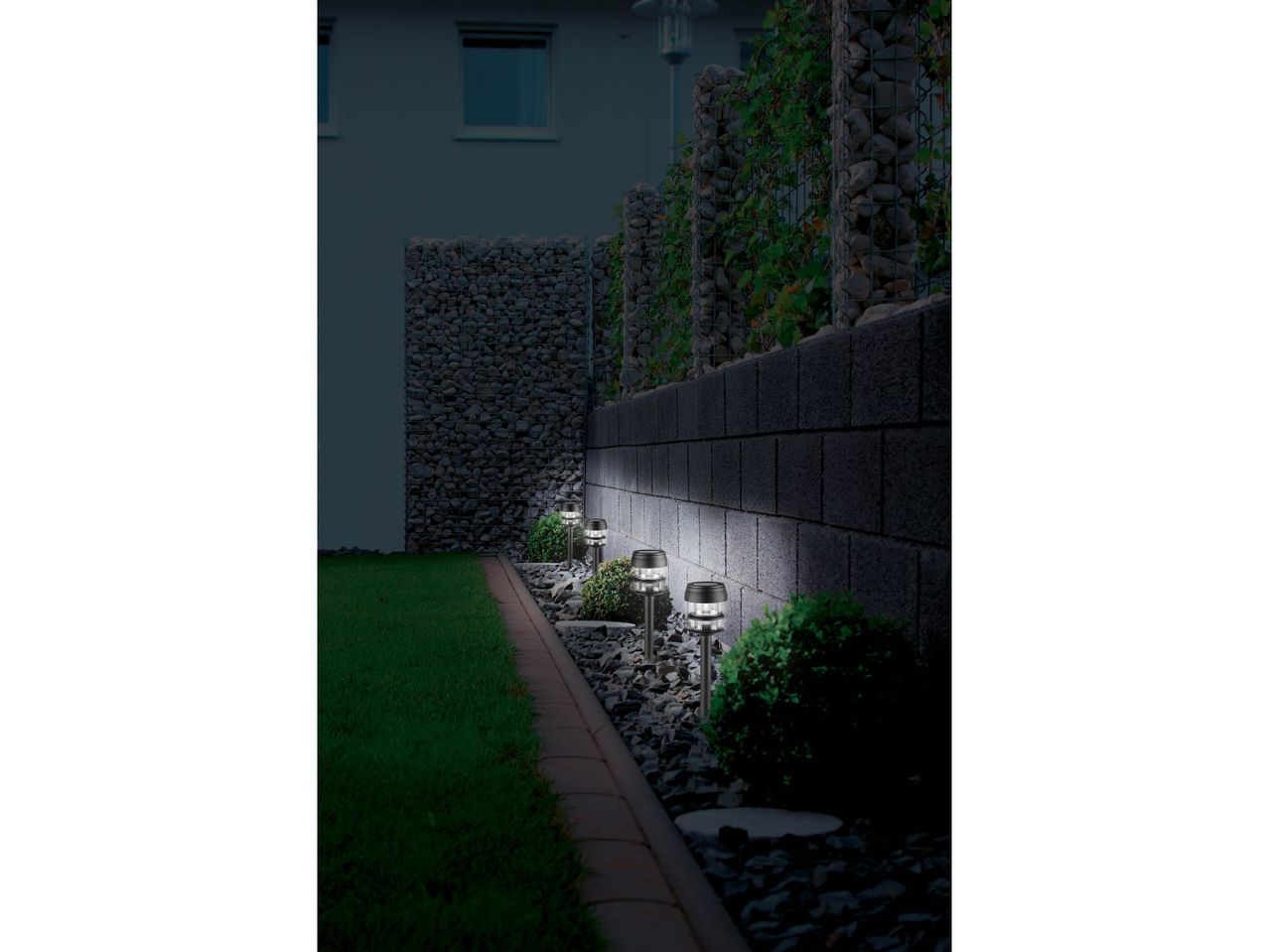Solar-powered garden lights illuminating a stone wall and pathway at night.