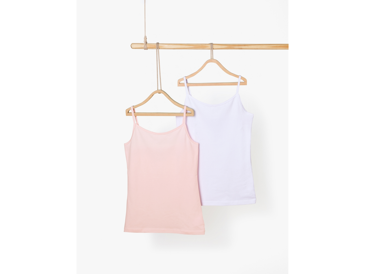 Zwei Trägertops, ein rosa und ein weißes, hängen an Holzbügeln.