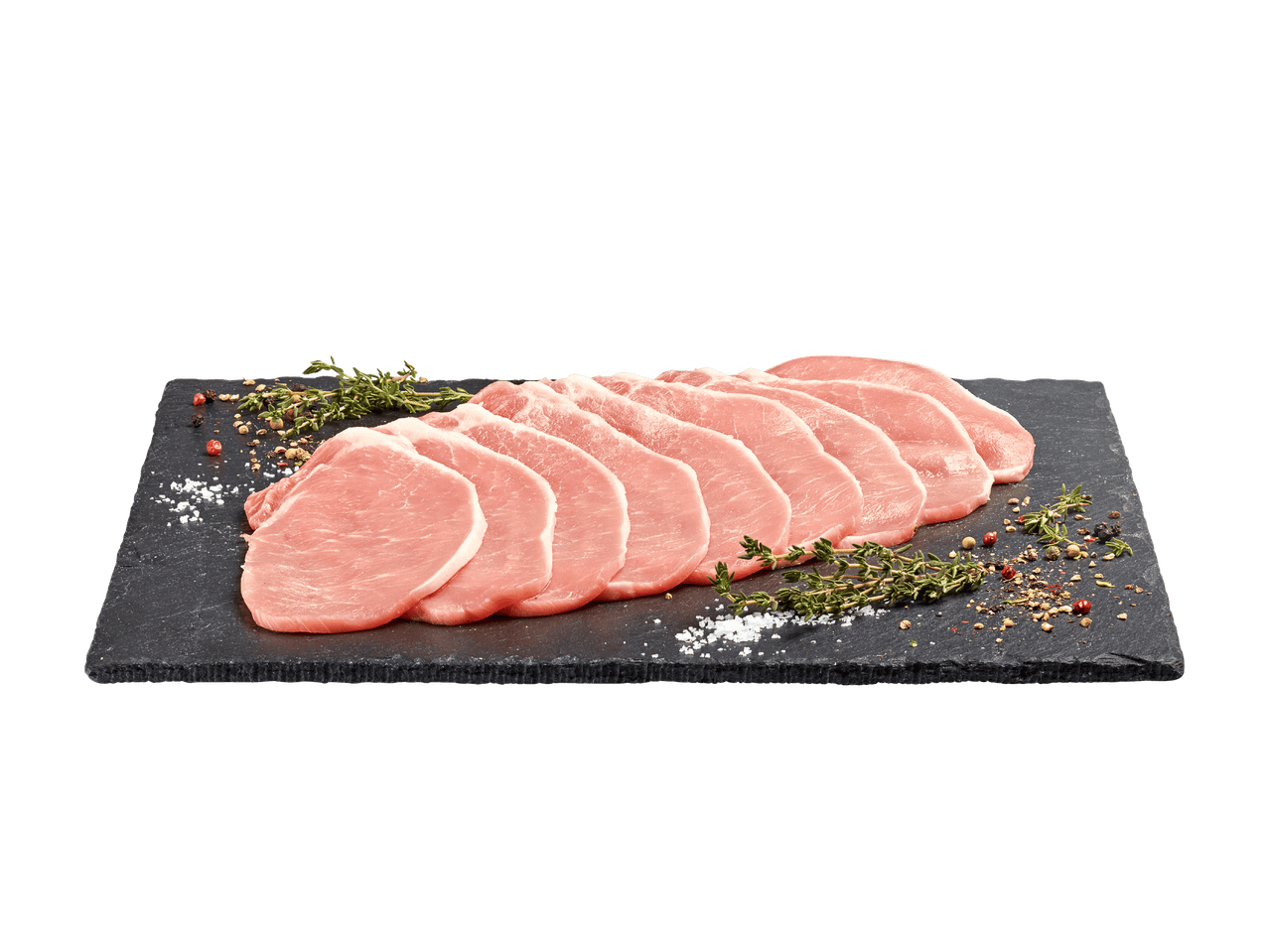 Rohe Schweinekoteletts mit Kräutern und Gewürzen auf einer dunklen Schieferplatte.
