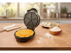 A waffle maker with a freshly made waffle on a wooden table.