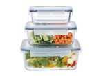 Stacked glass food containers with blue lids, filled with salad, carrots, and cucumbers.