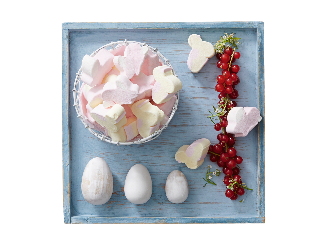 Paashaas marshmallows, rode bessen en paaseieren op een houten dienblad.