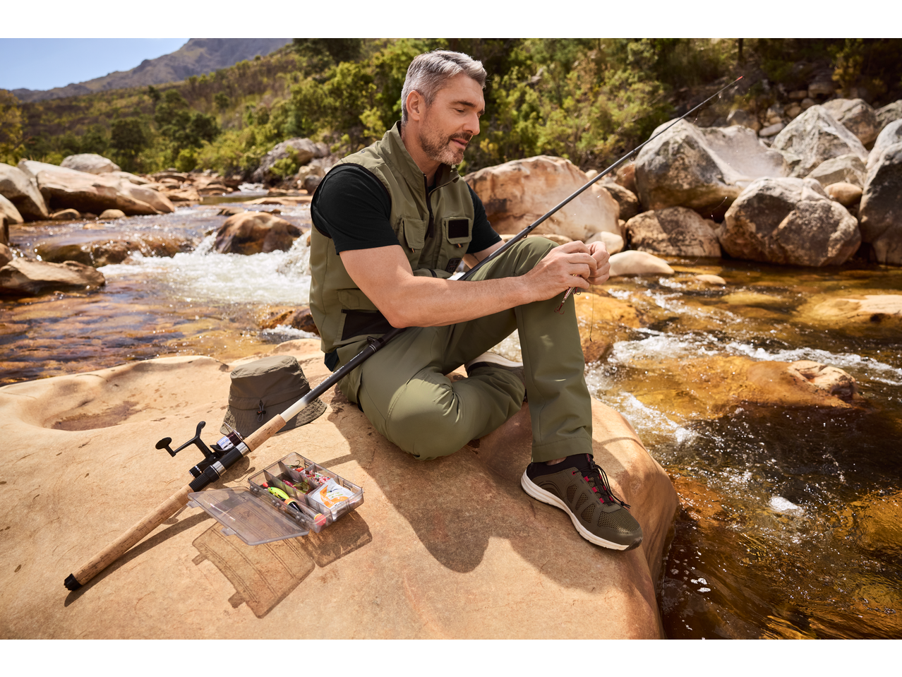 Bărbat cu set de echipament de pescuit CRIVIT stând lângă un râu.