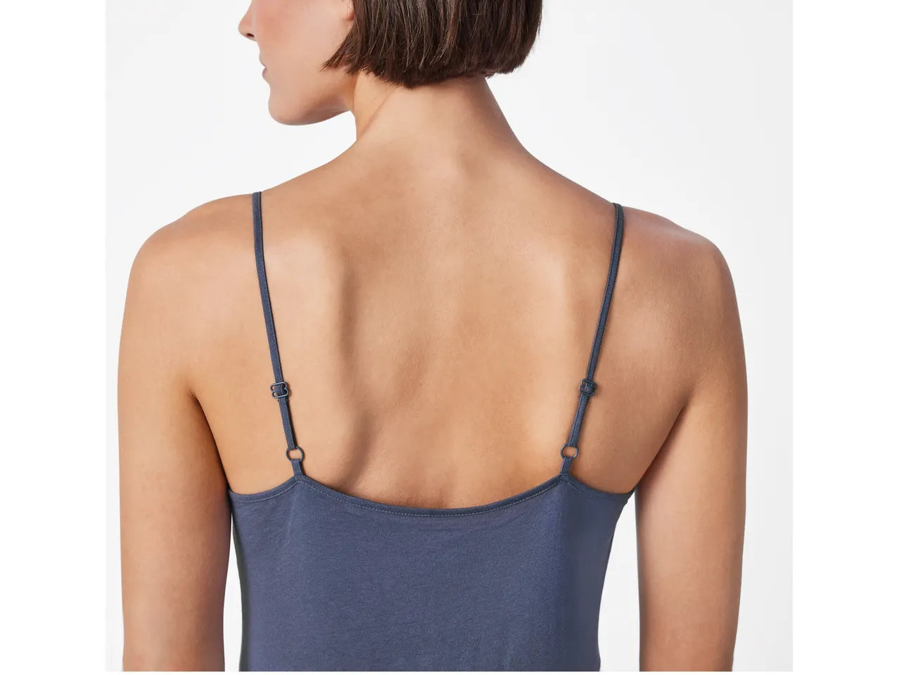 A woman wears a dark blue, thin camisole dress.