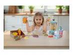 A young girl playing with a toy blender set, holding a toy cup and a recipe card for kiwi and grape juice.