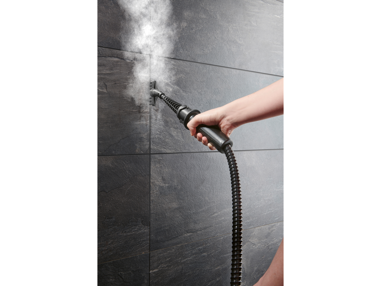 Uma pessoa limpa azulejos escuros de cerâmica com um limpador a vapor.