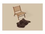 A wooden lounge chair with woven seat and backrest next to a brown faux fur rug.