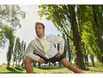 Un bărbat cu o jachetă sport Crivit se întinde într-un parc.
