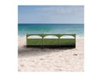 Green beach windbreak with three sections on a sandy beach with the ocean in the background.