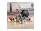 Stainless steel cookware set with a frying pan, saucepans, and fresh vegetables on a kitchen counter.
