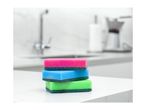Stack of three colorful kitchen sponges on a white countertop.