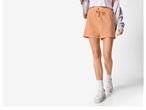 Femeie în pantaloni scurți de culoare piersică și adidași albi.