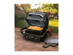 An air fryer with a basket of golden fries on a wooden table in a garden setting.