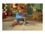 A happy child playing with a wooden stacking toy on a rug in a festive room.