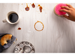 Colazione con caffè, bagel e spugna rosa Scrub Mommy su un tavolo.
