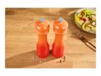 Orange salt and pepper grinders on a wooden table with a salad and fork.