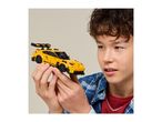 Boy holding a yellow toy sports car with a large rear spoiler.