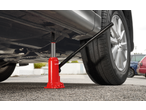 Red hydraulic bottle jack lifting a car, with a tire and wheel visible.