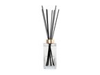 Reed diffuser with black sticks in a glass bottle with a gold cap