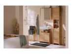 Bathroom with wooden furniture, white bathtub, shower, and green towels.