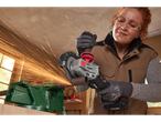 A woman uses a Parkside cordless angle grinder to cut a metal pipe in a workshop.