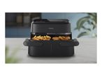 Black air fryer with two compartments, one filled with fries and the other with chicken drumsticks.