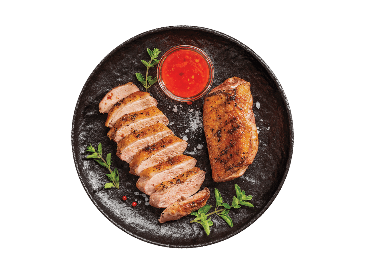 Anties krūtinėlė su raudonuoju padažu ir žolelėmis juodoje lėkštėje.