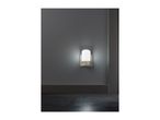 A white night light plugged into a gray wall, illuminating the dark floor.