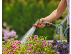 Mão regando flores com uma mangueira de jardim GARDENA.