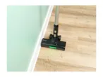 Cordless vacuum cleaner head with green LED lights on a wooden floor with dirt.