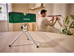 Um nível a laser Parkside em um tripé, projetando miras vermelhas em uma parede.
