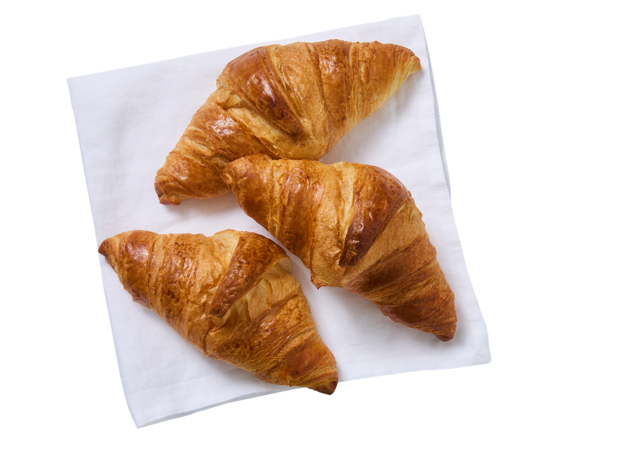 Três croissants de manteiga dourados sobre um guardanapo branco