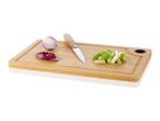 Red onion, spring onions, and knife on bamboo cutting board.