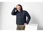 Uomo sorridente con giacca leggera blu navy e berretto beige.