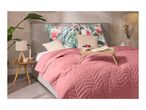 Bedroom with a pink quilted bedspread, tropical print pillows, and a wooden breakfast tray.