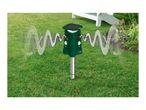 A green solar-powered animal repeller with ultrasonic waves in a garden setting.