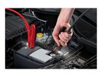 A person connecting black and red jumper cables to a car battery under the hood.